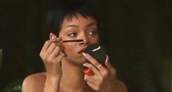 Rihanna wearing stripey dress applying make up